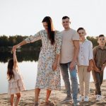 A family of five enjoys a serene lakeside vacation at sunset, capturing precious moments together.